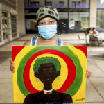 FIT student holds up Juneteenth painting