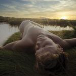 image of nude male on grass near body of water photographed by Ron Amato
